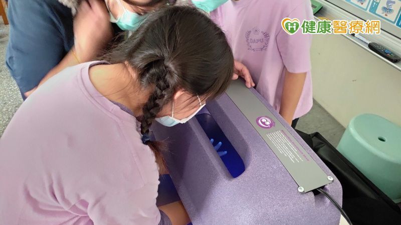 學童洗完手,透過螢光燈輔助檢視手部衛生,檢測自己手上還有沒有乳液殘留。(照/由桃園長庚紀念醫院提供)