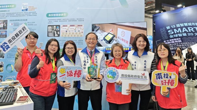 南投縣政府衛生局團隊在「智慧城市展」展區前，以全國首創「送藥到府服務系統」創新應用獲得優勝。核心推動成員共同合影，衛生局長陳南松（中）帶領團隊展示「一級棒」、「南投好棒」等手板，展現南投縣推動智慧醫療與照顧鄉親的決心與士氣。(圖/南投縣政府提供)